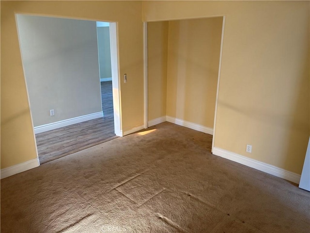 unfurnished room with carpet flooring and baseboards
