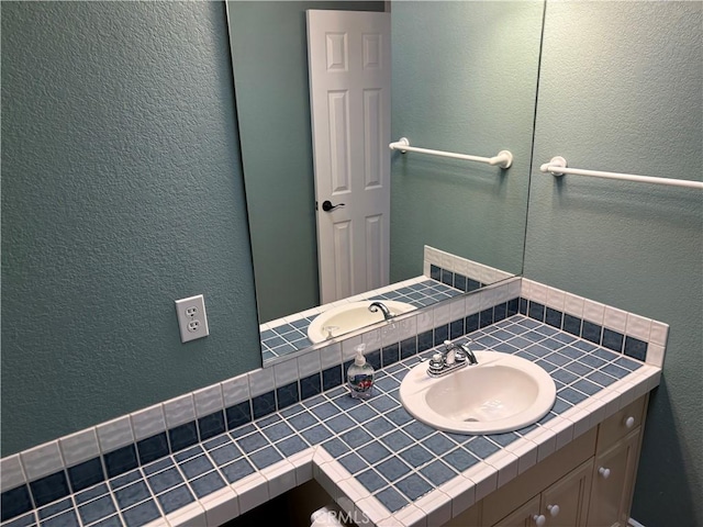 bathroom with a textured wall and vanity