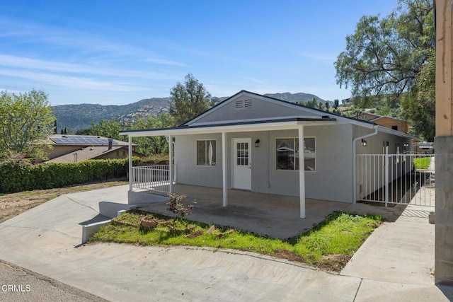 view of front of property featuring stucco siding, a mountain view, fence, and covered porch