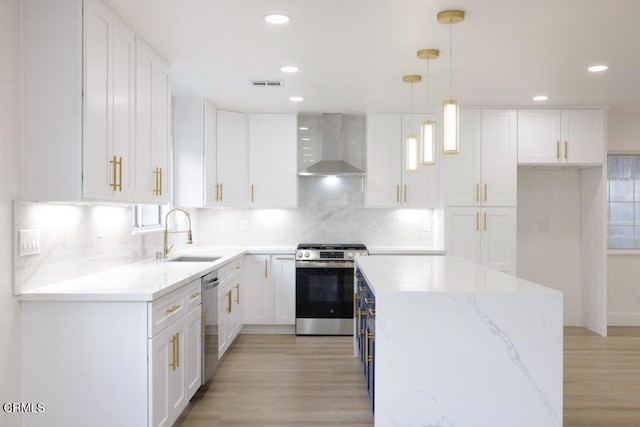 kitchen featuring a sink, light wood-style floors, wall chimney exhaust hood, appliances with stainless steel finishes, and visible vents