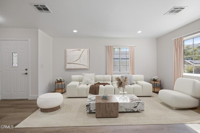 living room with recessed lighting, wood finished floors, and visible vents