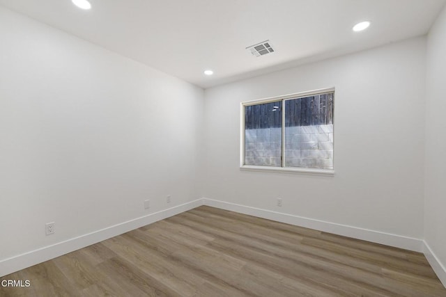 empty room featuring wood finished floors, visible vents, and recessed lighting