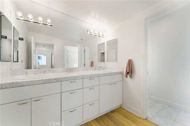 full bathroom featuring a sink, baseboards, and double vanity
