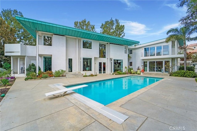 back of house with an outdoor pool, a patio, and stucco siding
