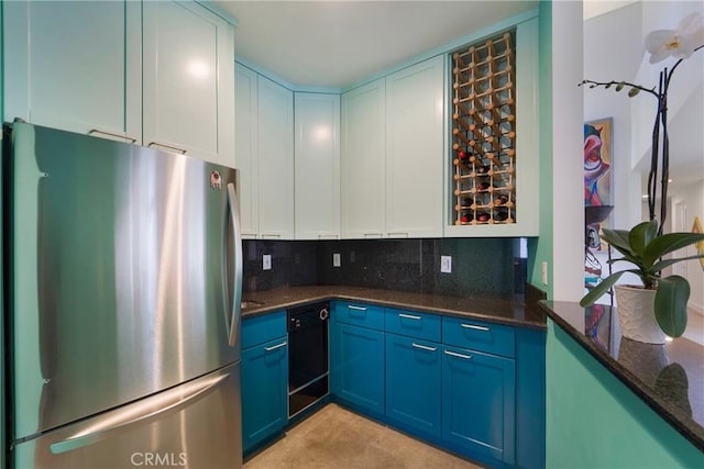 kitchen with decorative backsplash, white cabinetry, freestanding refrigerator, and dark stone countertops