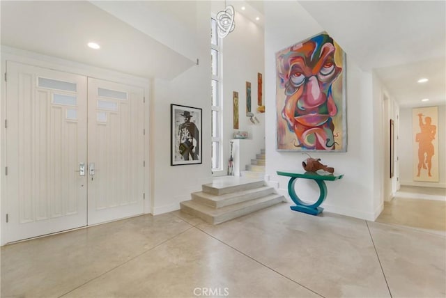 entrance foyer with concrete flooring, baseboards, recessed lighting, and stairs