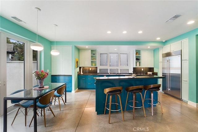 kitchen featuring dark countertops, visible vents, open shelves, and built in fridge