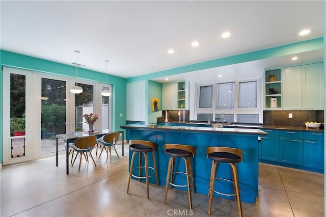 kitchen with dark countertops, backsplash, open shelves, and a kitchen bar