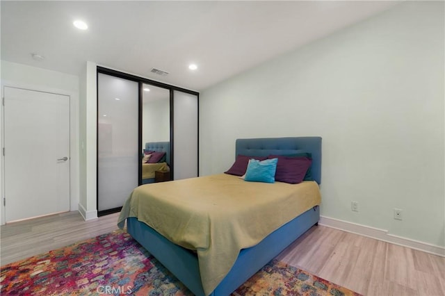 bedroom with visible vents, a closet, baseboards, and wood finished floors