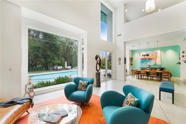 living area featuring tile patterned floors, a high ceiling, baseboards, and visible vents