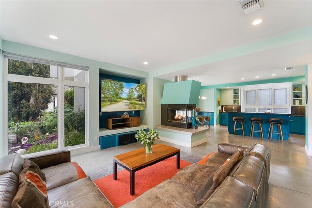 living room with visible vents, recessed lighting, a multi sided fireplace, and finished concrete flooring
