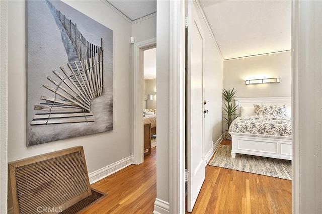 hall with crown molding, wood finished floors, baseboards, and visible vents