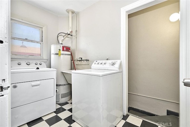 laundry room featuring laundry area, washing machine and clothes dryer, secured water heater, and tile patterned floors