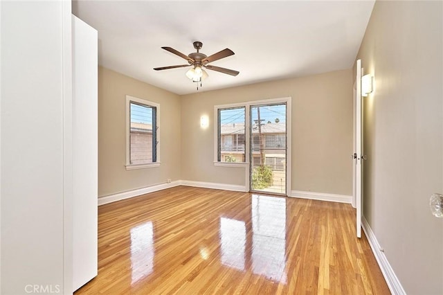 spare room featuring ceiling fan, light wood-type flooring, and baseboards
