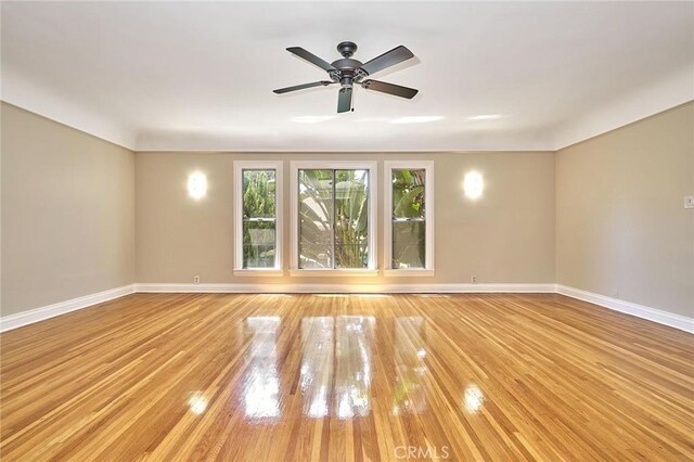 empty room with light wood-style floors, baseboards, and a ceiling fan