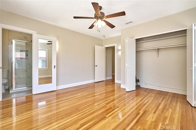 unfurnished bedroom featuring light wood-type flooring, a closet, ensuite bath, visible vents, and baseboards