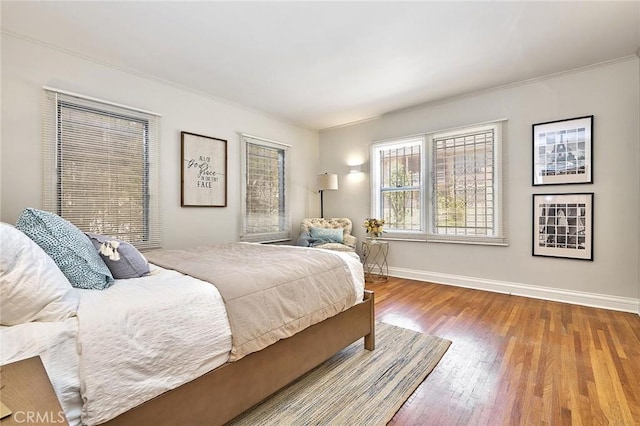 bedroom featuring baseboards, ornamental molding, and wood finished floors