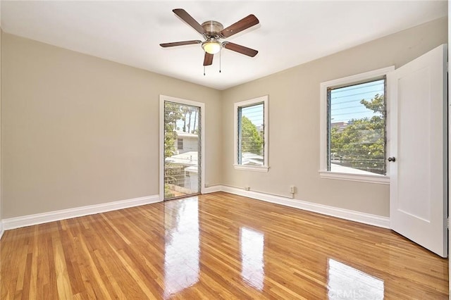 empty room featuring ceiling fan, light wood finished floors, and baseboards