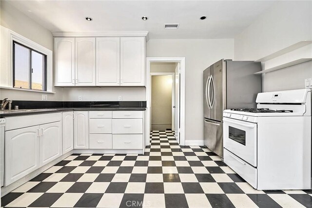 kitchen with white range with gas stovetop, white cabinets, visible vents, a sink, and tile patterned floors