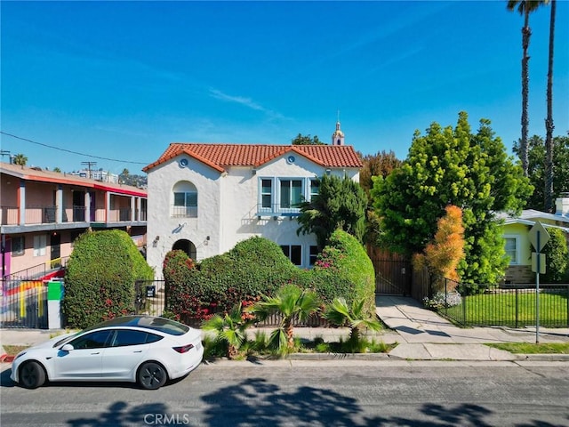 view of front facade featuring a tile roof, fence, and stucco siding