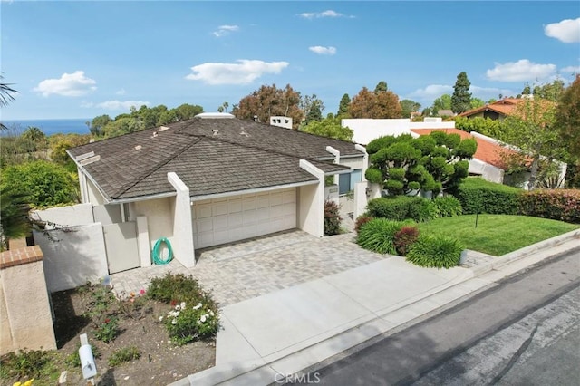 view of front facade featuring stucco siding, a garage, decorative driveway, and fence