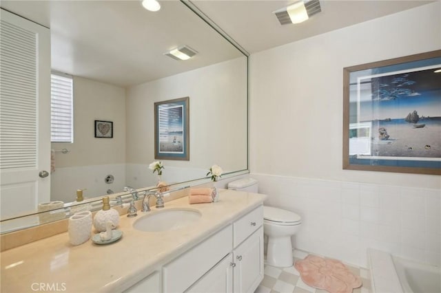 bathroom with a garden tub, vanity, toilet, and a wainscoted wall