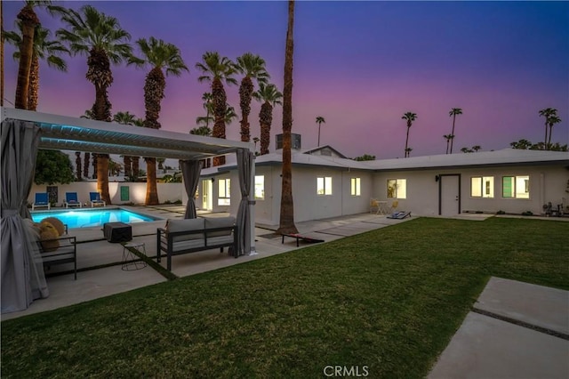 1657 S Sunrise Way, Palm Springs, CA 92264 - back of property at dusk with stucco siding, an outdoor pool, a patio, and a yard