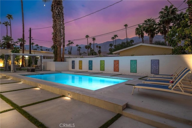 1657 S Sunrise Way, Palm Springs, CA 92264 - pool at dusk with a fenced in pool, a mountain view, fence, and a patio