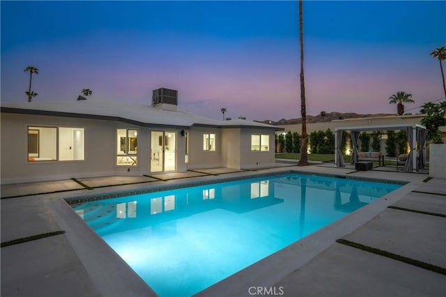 1657 S Sunrise Way, Palm Springs, CA 92264 - pool at dusk featuring a patio, central air condition unit, and an outdoor pool