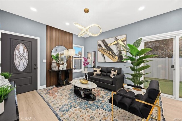 living room featuring recessed lighting, an inviting chandelier, wood finished floors, and baseboards