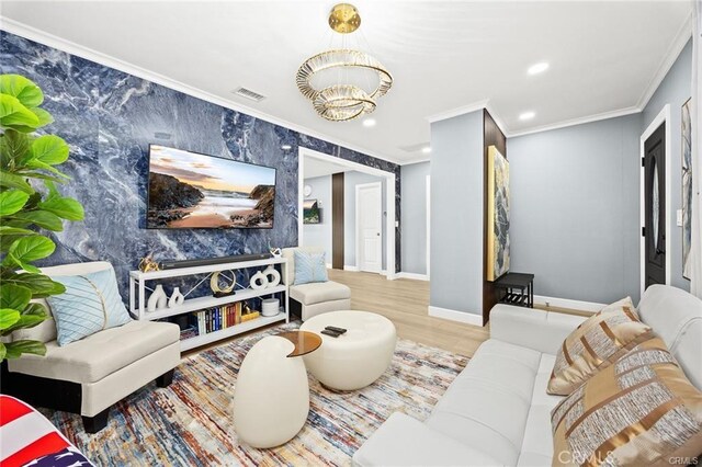living room featuring crown molding, wood finished floors, an inviting chandelier, baseboards, and visible vents