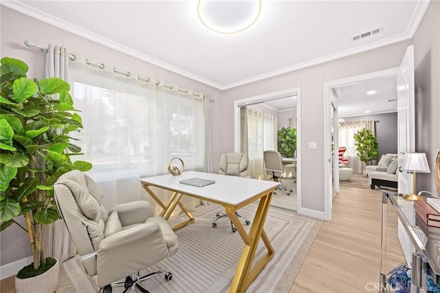 office featuring light wood finished floors, baseboards, visible vents, and ornamental molding