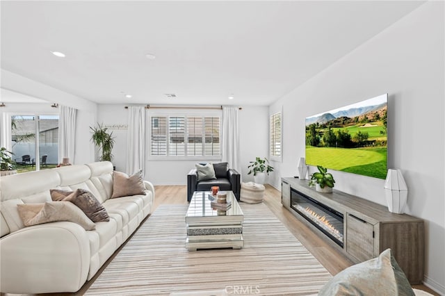 5053 Moon Eye Way, Hemet, CA 92545 - living room with a wealth of natural light, light wood-style flooring, a glass covered fireplace, and recessed lighting