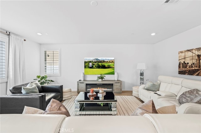 5053 Moon Eye Way, Hemet, CA 92545 - living room with wood finished floors, visible vents, a glass covered fireplace, and recessed lighting