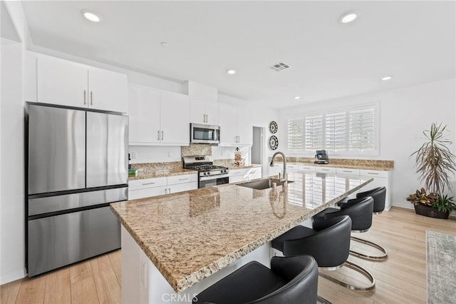 5053 Moon Eye Way, Hemet, CA 92545 - kitchen with a sink, a kitchen breakfast bar, stainless steel appliances, visible vents, and white cabinets