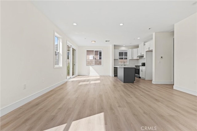 unfurnished living room with baseboards, light wood-style flooring, and recessed lighting