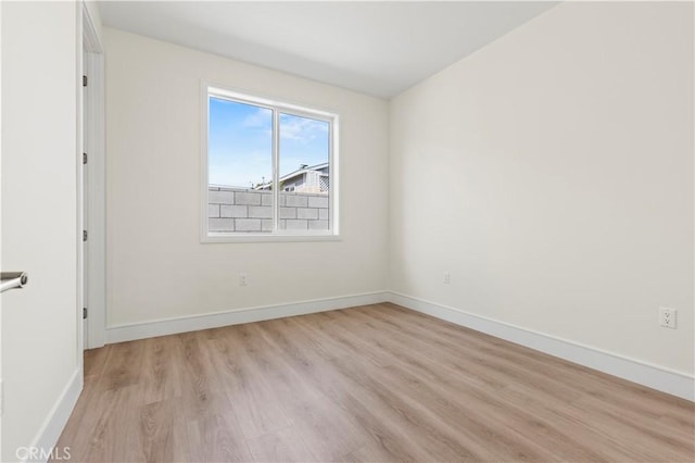 spare room featuring baseboards and light wood-type flooring