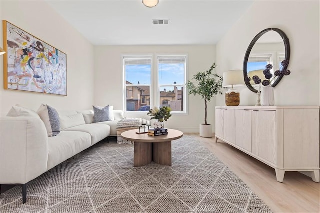 living room with baseboards, light wood-style flooring, and visible vents