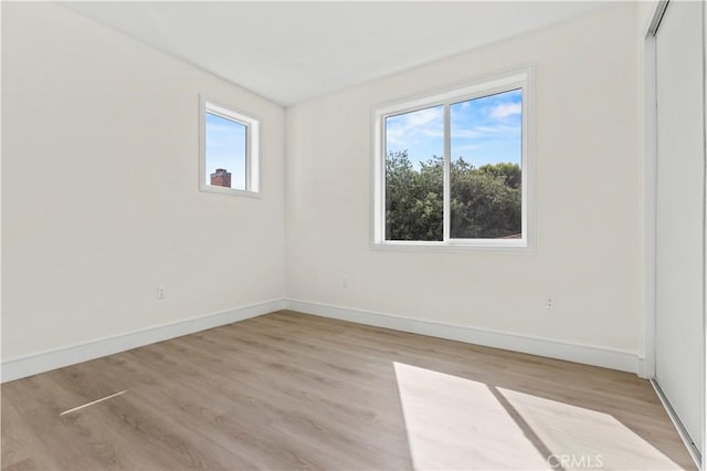 unfurnished room featuring baseboards and light wood-type flooring