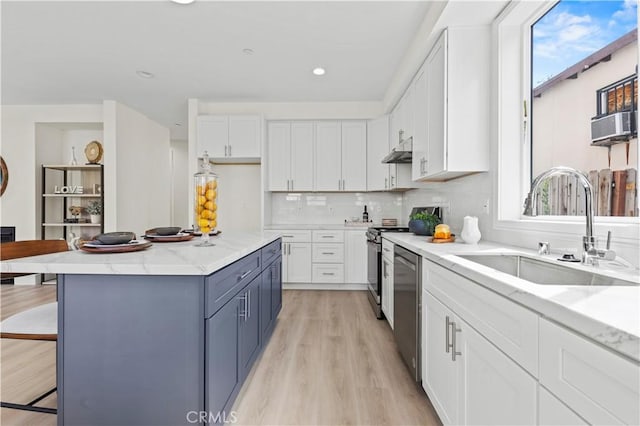 kitchen featuring white cabinets, under cabinet range hood, a sink, and a healthy amount of sunlight