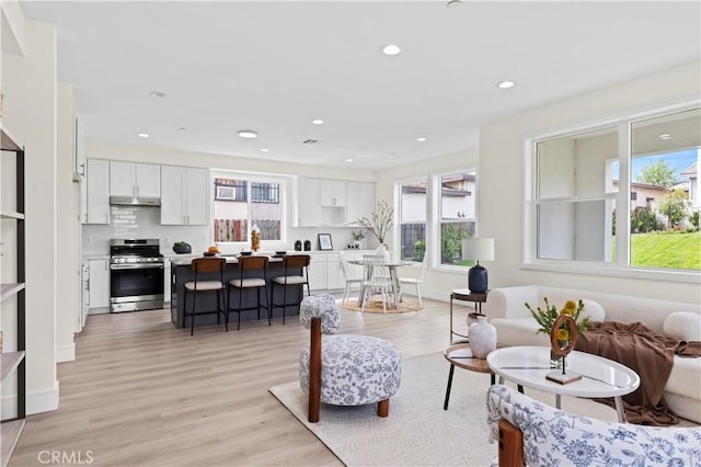 living area featuring baseboards, recessed lighting, and light wood-type flooring