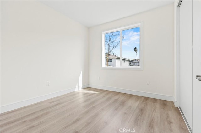 empty room featuring baseboards and light wood-type flooring