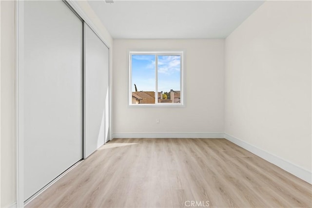 unfurnished bedroom featuring a closet, baseboards, and light wood-type flooring