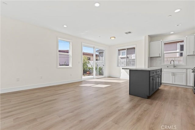 kitchen featuring light countertops, baseboards, tasteful backsplash, a sink, and light wood-style floors