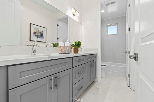 bathroom featuring toilet, a sink, marble finish floor, visible vents, and double vanity