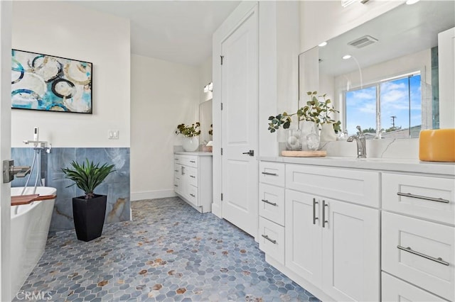 bathroom with a soaking tub, visible vents, and vanity