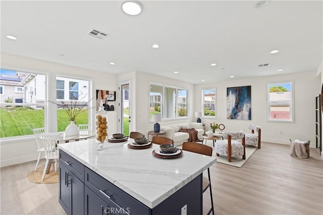 kitchen featuring a kitchen breakfast bar, a kitchen island, recessed lighting, and light wood-type flooring