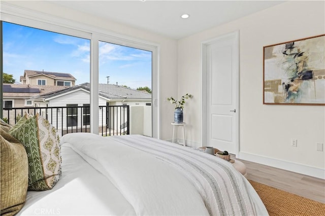 bedroom with baseboards, wood finished floors, recessed lighting, and access to outside