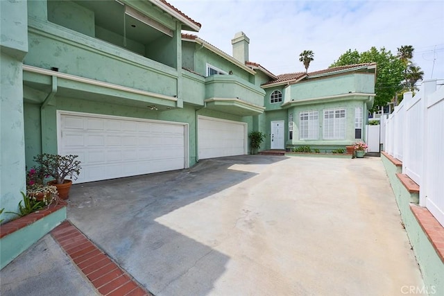 385 Park Ave, Long Beach, CA 90814 - front facade featuring a garage, stucco siding, a chimney, a tiled roof, and driveway