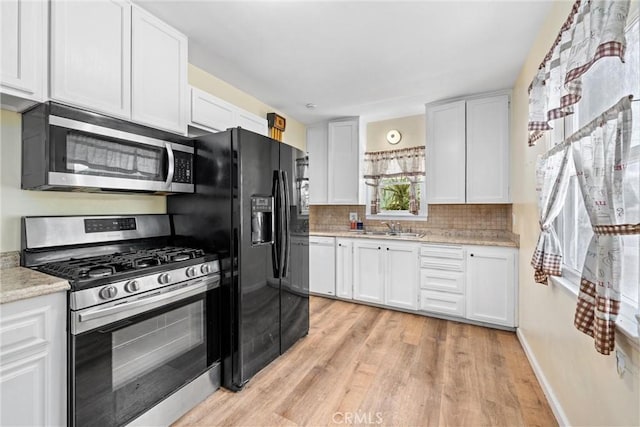 681 E Washington Ave, San Jacinto, CA 92583 - kitchen with stainless steel appliances, a sink, light wood-type flooring, and white cabinetry